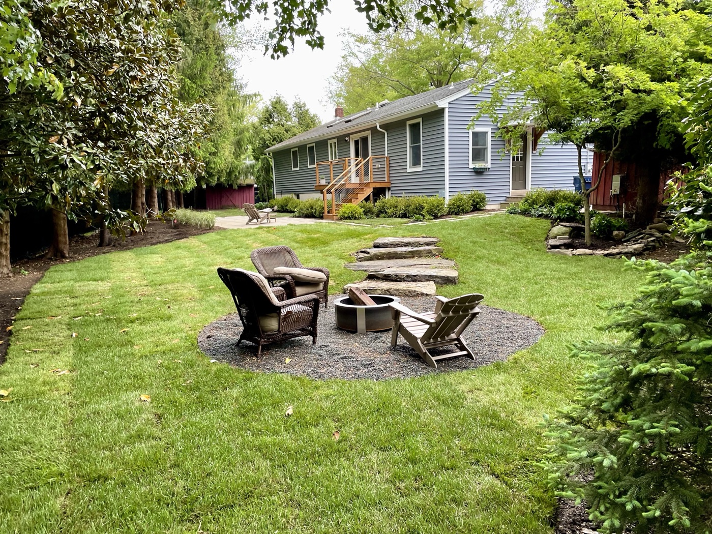 After: fully landscaped backyard with fire pit seating area and lush lawn
