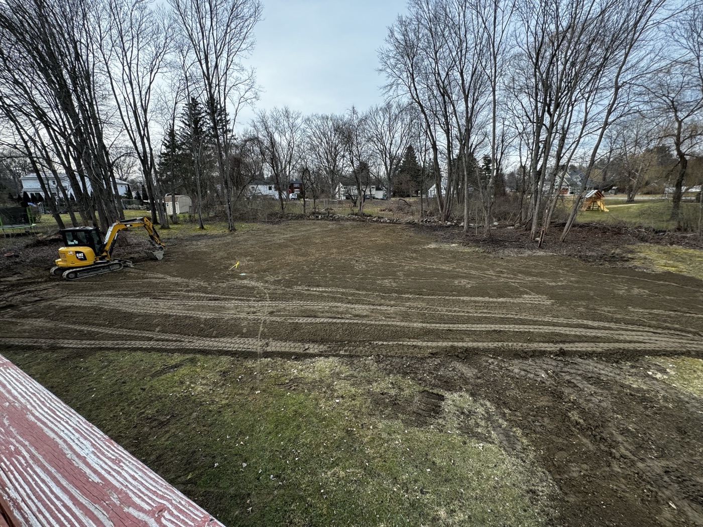 Before: bare graded yard with excavator after clearing